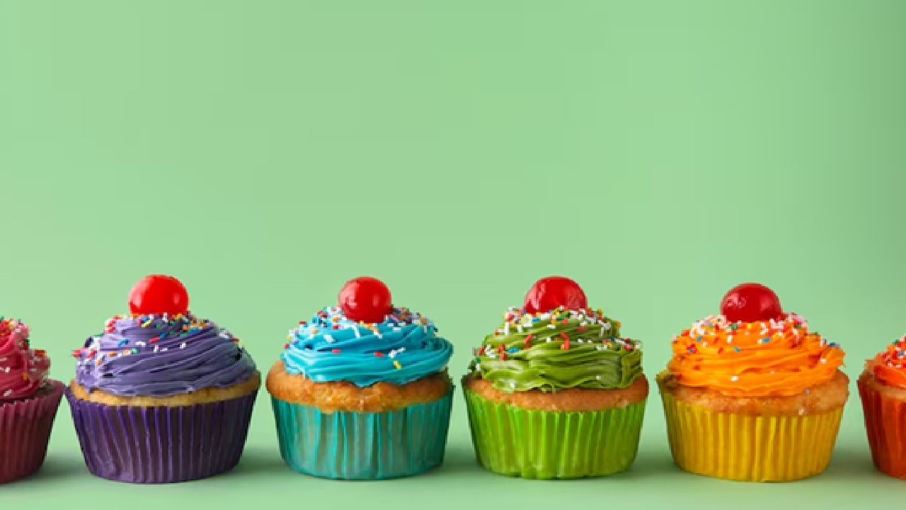 Sprinkle a tiny amount of edible glitter and micro sprinkles over vanilla frosting filled red velvet cupcakes.