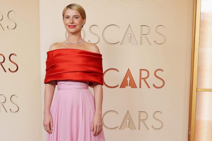 Jessie Buckley looked ravishing in a striking red-and-pink satin gown featuring an off-the-shoulder layered bodice and a long train.